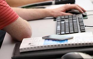 电脑键盘，记事本，电话，和男性的手在鼠标